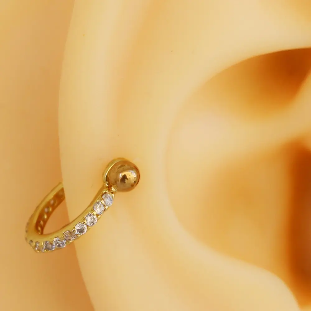 Altın rengi zirkon taşlı helix, kıkırdak piercing kulakta genel görünüm