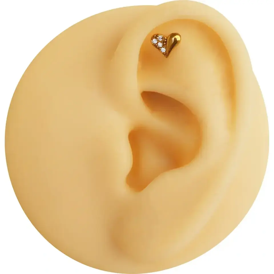 Helix bölgesinde romantik bir duruş sergileyen altın sarısı taşlı kalp kıkırdak piercing