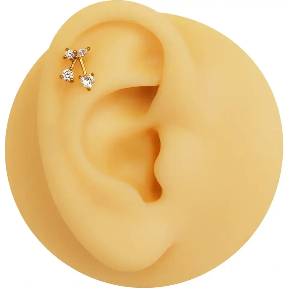 Helix bölgesinde neşeli bir duruş sergileyen altın sarısı taşlı kiraz kıkırdak takısı