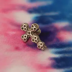 Kulak üzerinde conch ve tragus uyumlu vidalı kurukafa haç piercing görünümü