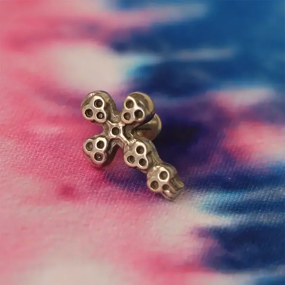 Kulak üzerinde conch ve tragus uyumlu vidalı kurukafa haç piercing görünümü