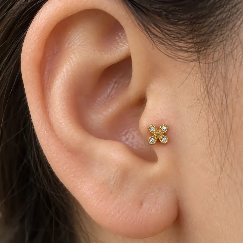 Kulak üzerinde yonca figürlü altın rengi tragus helix kıkırdak piercing