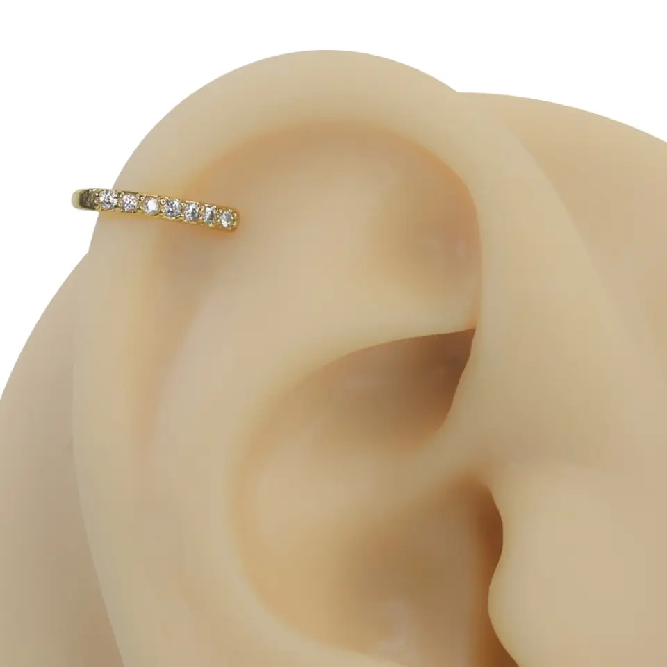 Altın rengi ışık seli zirkon taşlı sıkıştırma kıkırdak piercing modelinin kulak üzerindeki lüks duruşu