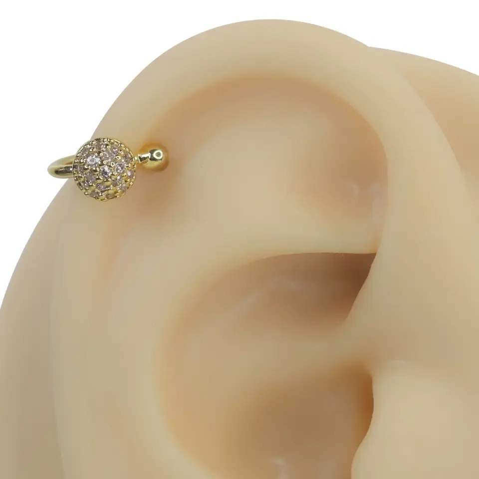 Altın rengi ışık küresi zirkon taşlı sıkıştırma kıkırdak piercing modelinin kulak üzerindeki parıltılı ve lüks duruşu