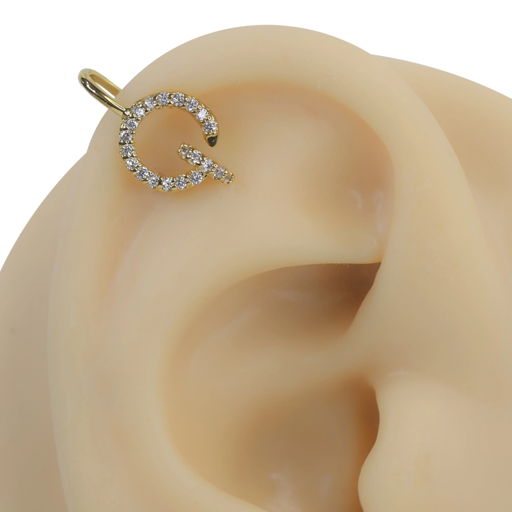 Altın rengi gizemli mühür zirkon taşlı sıkıştırma kıkırdak piercing modelinin kulak üzerindeki parıltılı ve mistik duruşu