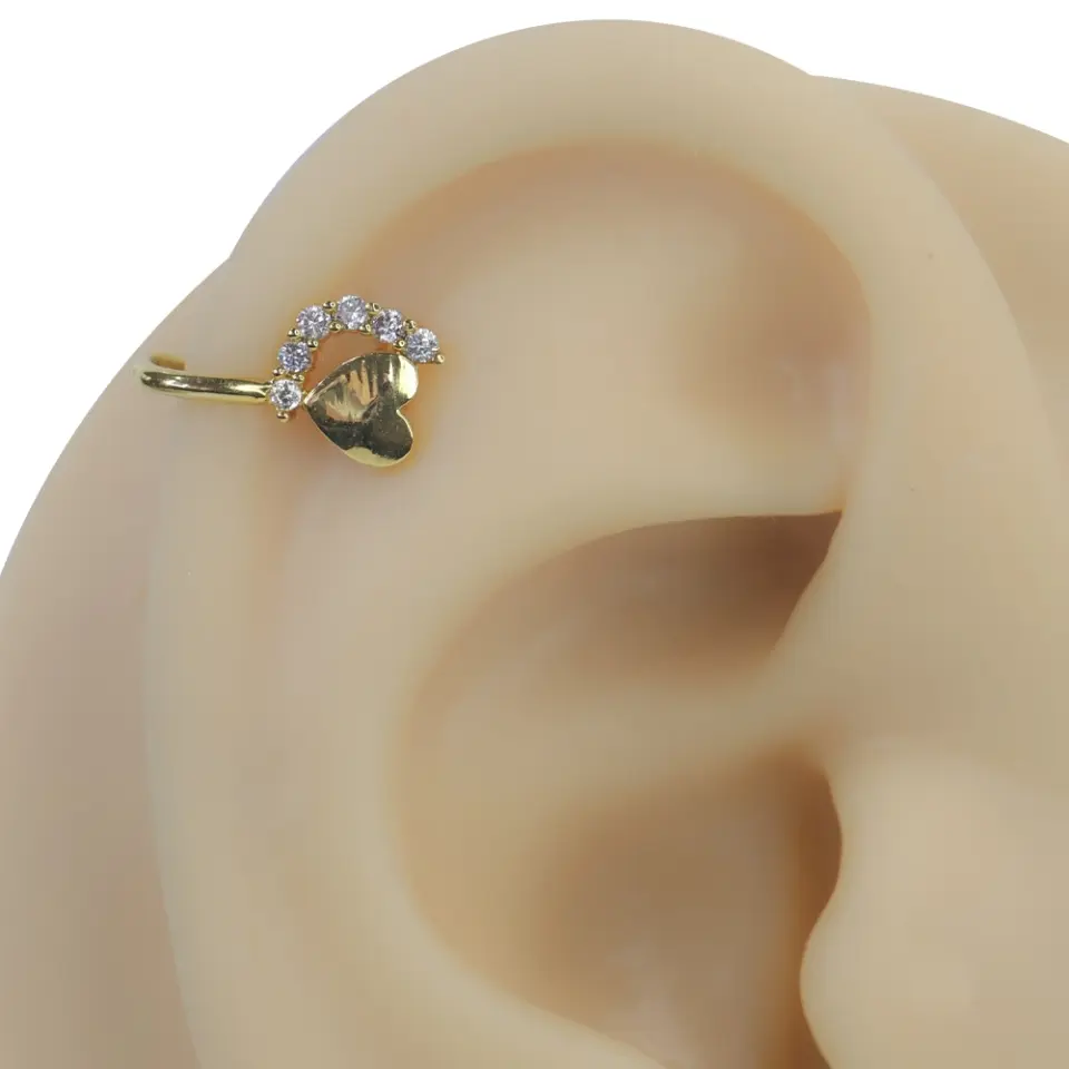 Altın rengi ışığın kalbi zirkon taşlı sıkıştırma kıkırdak piercing modelinin kulak üzerindeki lüks ve parıltılı duruşu