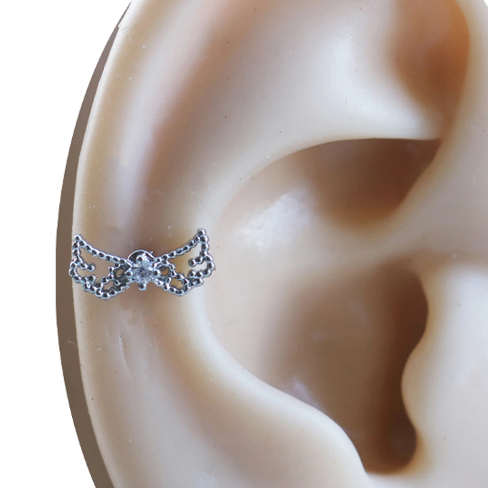 Kulak üzerinde sergilenen zirkon taşlı gümüş renkli tragus helix kıkırdak piercing modeli