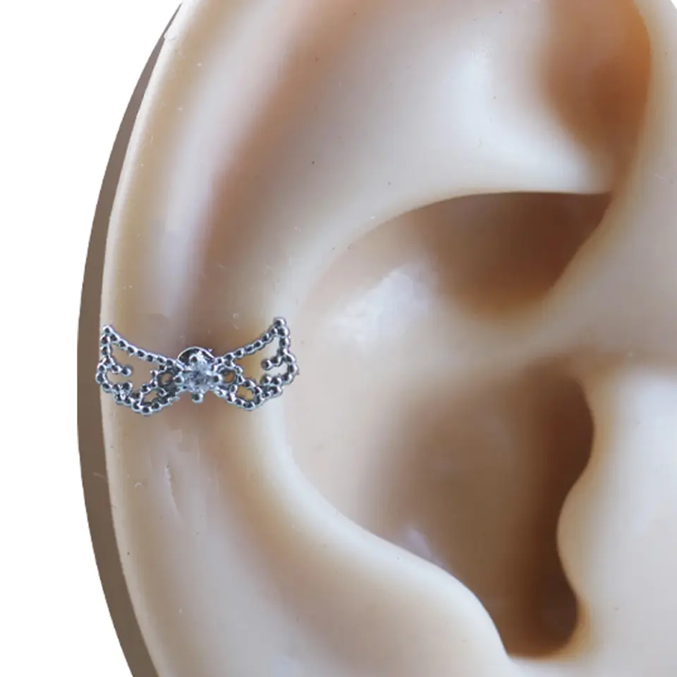 Kulak üzerinde sergilenen zirkon taşlı gümüş renkli tragus helix kıkırdak piercing modeli