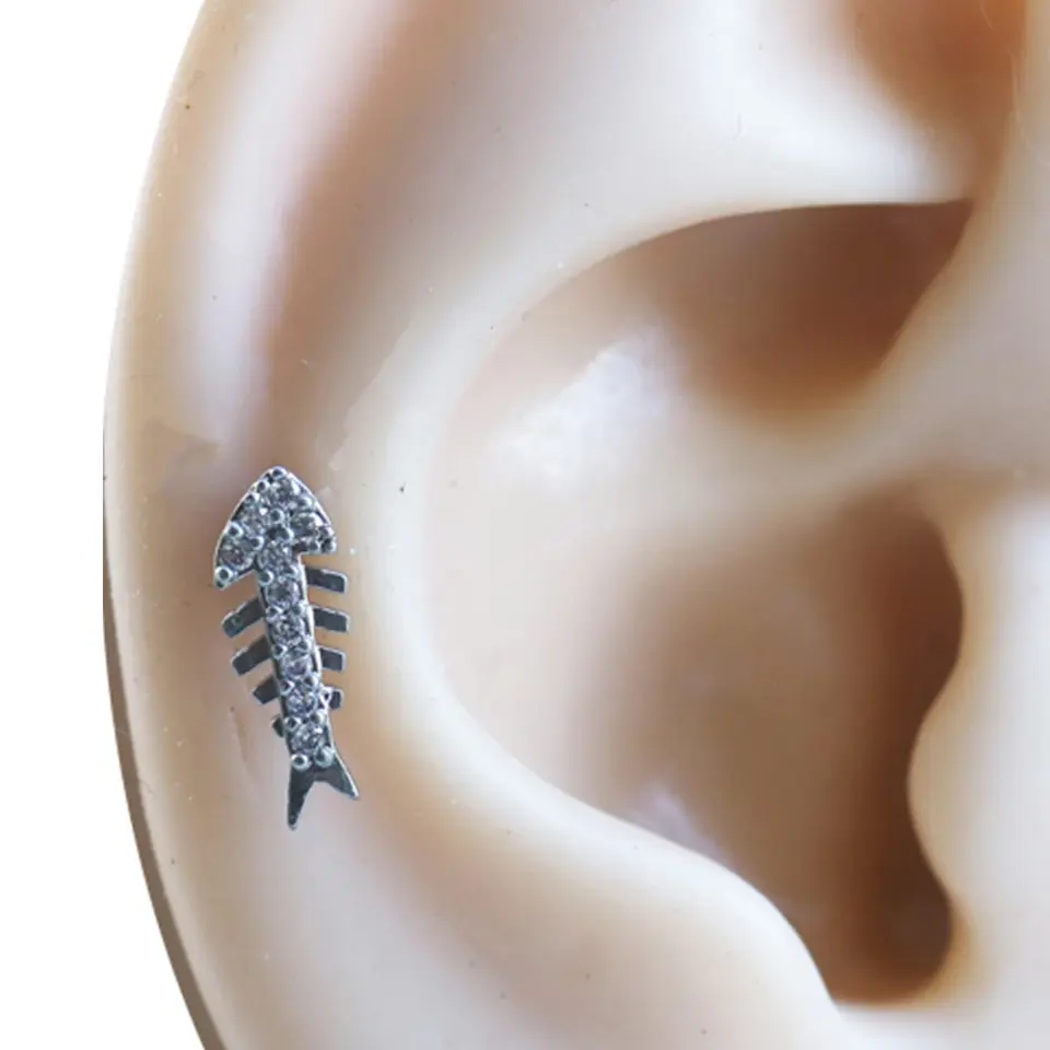 Kıkırdak bölgesinde sergilenen kılçık formlu zirkon taşlı gümüş renkli piercing