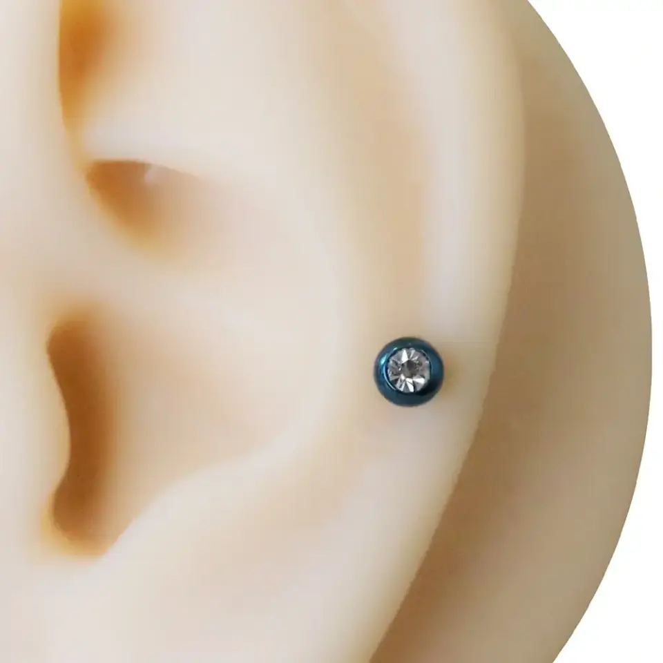 Kulak tragus ve kıkırdak bölgesinde mavi renkli taşlı piercing duruşu