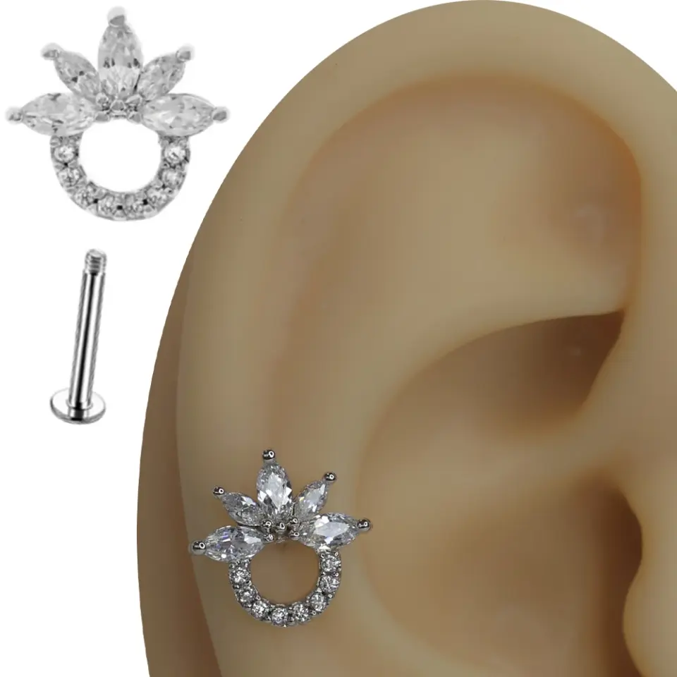 Kulak kıkırdağında sergilenen zirkon taşlı güneş figürlü tragus helix kıkırdak piercing.