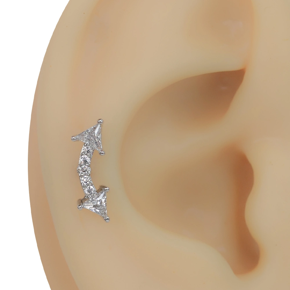 Kulak üzerinde kavisli yapısıyla sergilenen gümüş rengi tragus helix kıkırdak piercing.