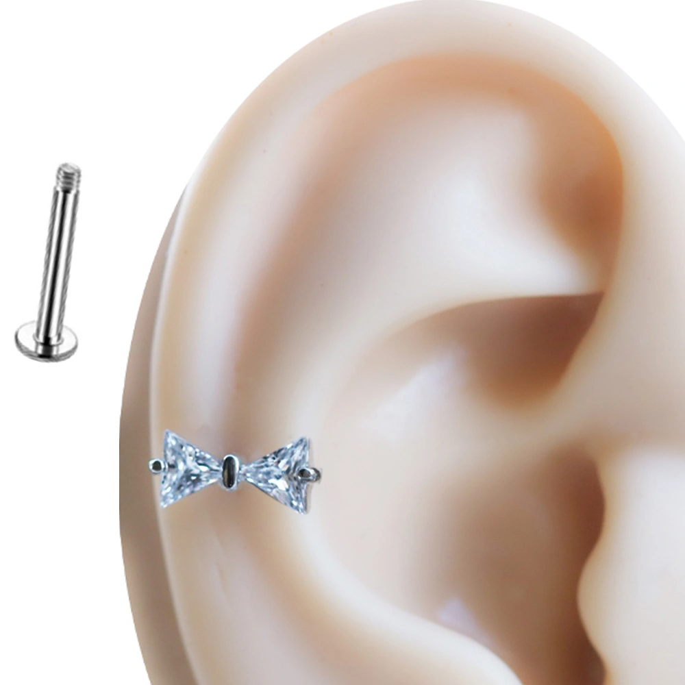 Kulak üzerinde sergilenen zirkon taşlı kelebek figürlü düz arkalı tragus helix kıkırdak piercing.