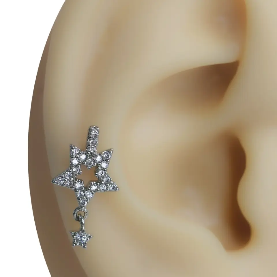 Kulak kıkırdağında sergilenen zirkon taşlı akan yıldız figürlü tragus helix kıkırdak piercing