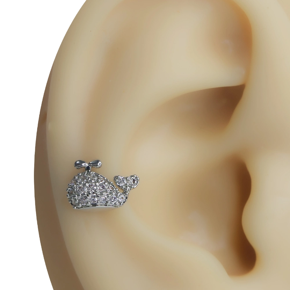 Kulak üzerinde sergilenen zirkon taşlı balina figürlü tragus helix kıkırdak piercing modeli