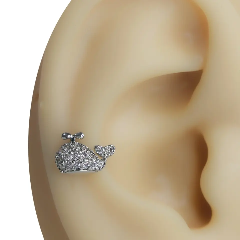 Kulak üzerinde sergilenen zirkon taşlı balina figürlü tragus helix kıkırdak piercing modeli