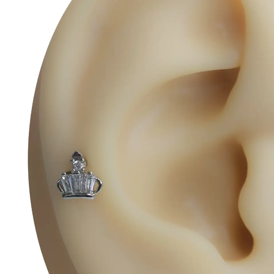 Işığın Hükmü taç figürlü gümüş rengi tragus helix kıkırdak piercing modelinin kulaktaki duruşu