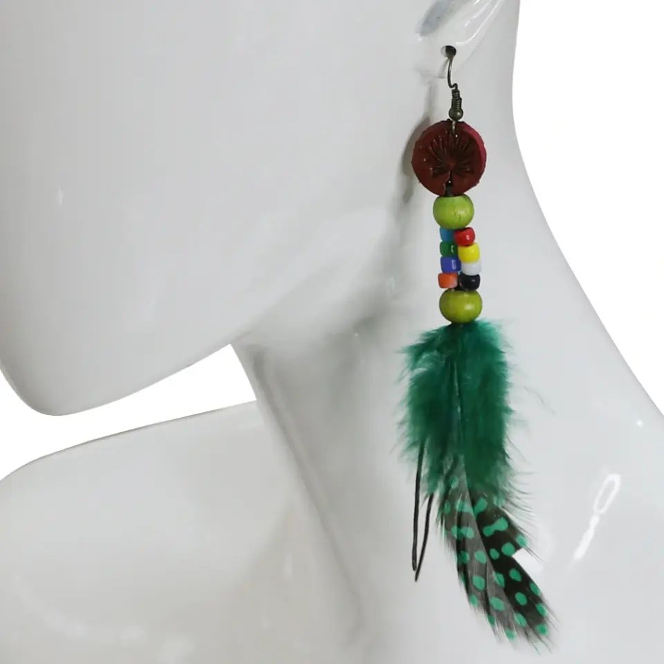 Kulakta sergilenen yeşil tüy ve puantiyeli detaylara sahip el yapımı deri küpe