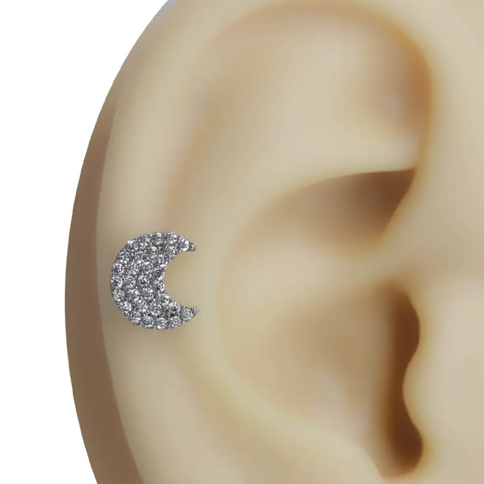 Gümüş renkli hilal formunda zirkon taşlı tragus helix kıkırdak piercing kulak üzeri görünümü