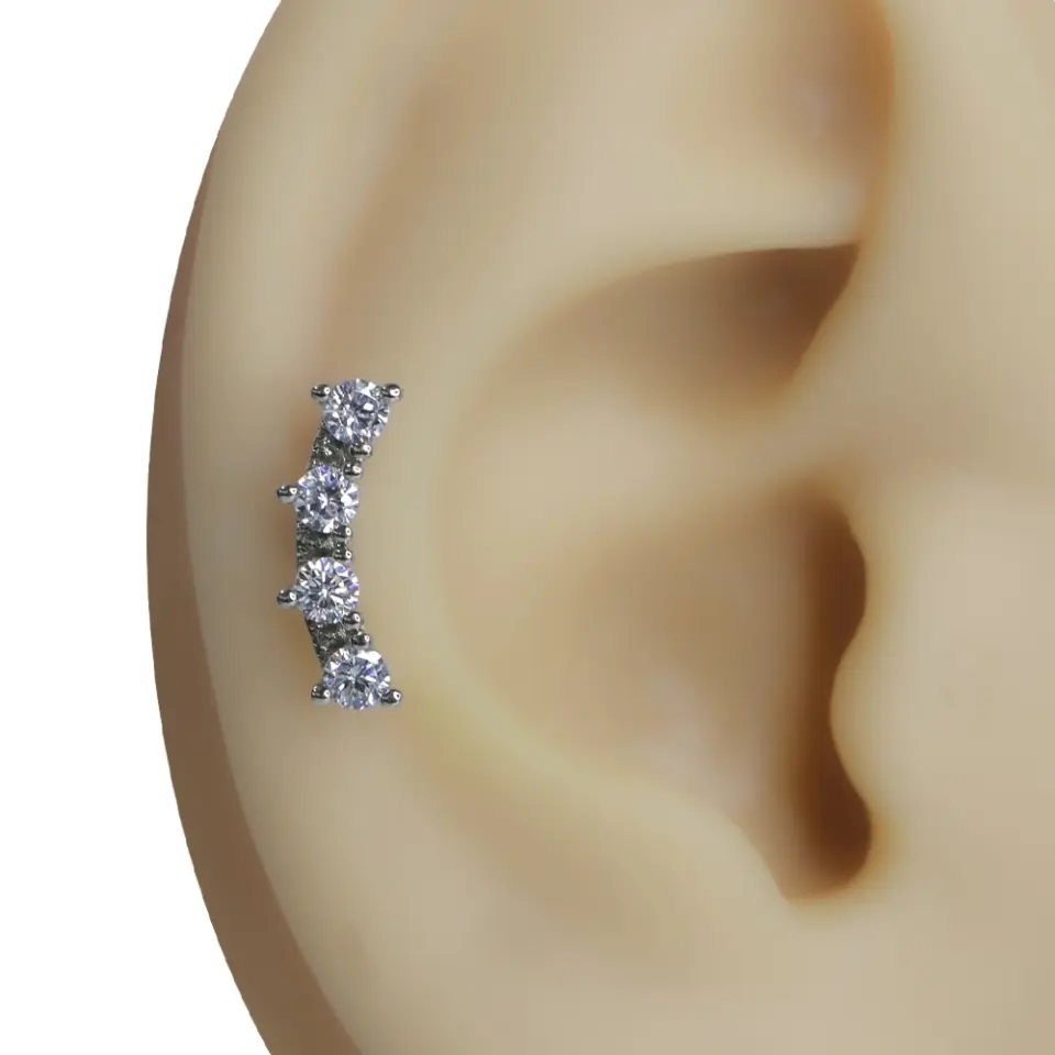 Gümüş renkli kavisli dörtlü zirkon taşlı tragus helix kıkırdak piercing kulak üzeri görünümü