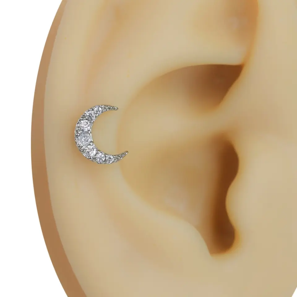 Kulak kıkırdağı üzerinde sergilenen Hilal model zirkon taşlı gümüş rengi tragus helix kıkırdak piercing