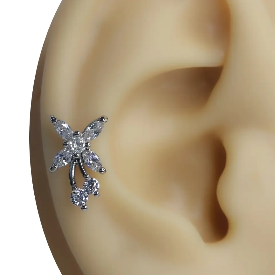 Kulak üzerinde parlayan çiçek formlu bahar esintisi tragus helix kıkırdak piercing.