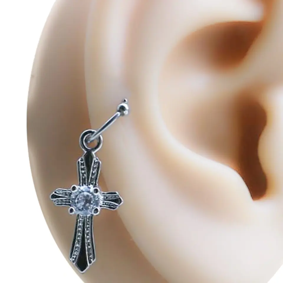 Kulak üzerinde sergilenen haç figürlü halka tragus helix kıkırdak piercing tasarımı.