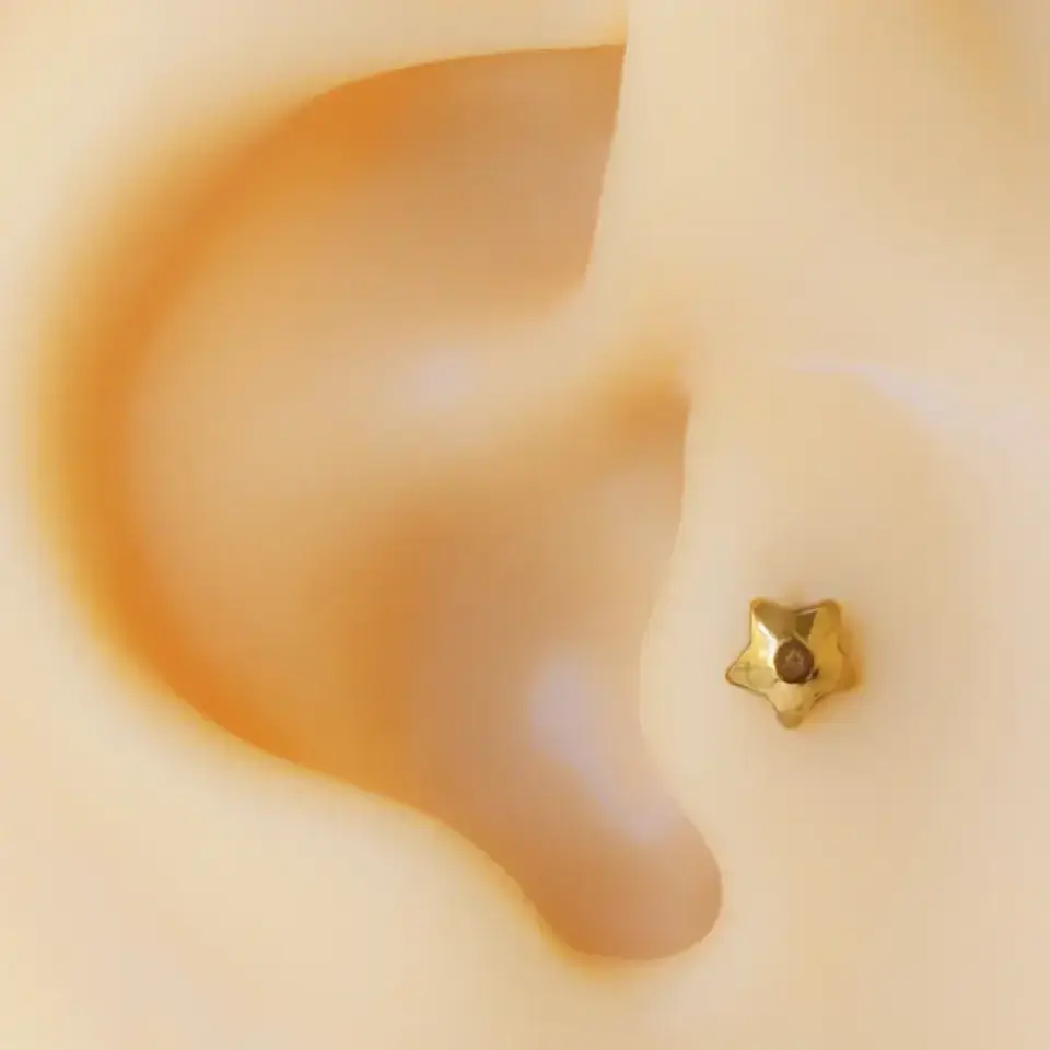 Altın renk minimal yıldız modelli cerrahi çelik tragus piercing.