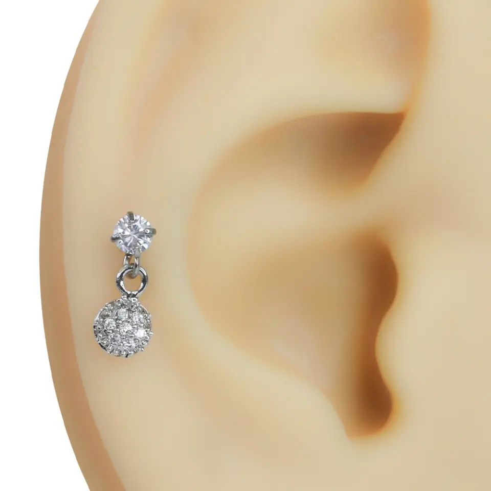Kulağın kıkırdak bölgesinde sergilenen sallantılı zirkon taşlı gümüş rengi taşlı top model tragus helix kıkırdak piercing