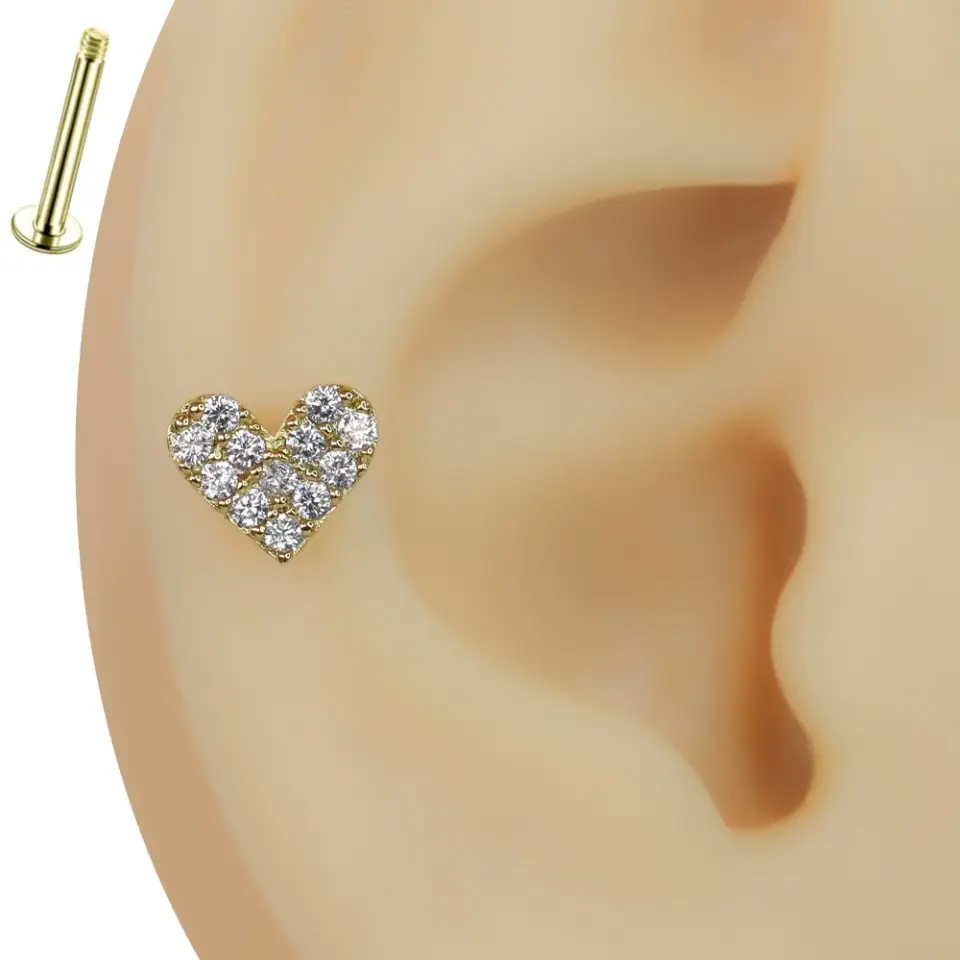 Kulak üzerinde sergilenen zirkon taşlı altın kalp figürlü tragus helix kıkırdak piercing tasarımı.