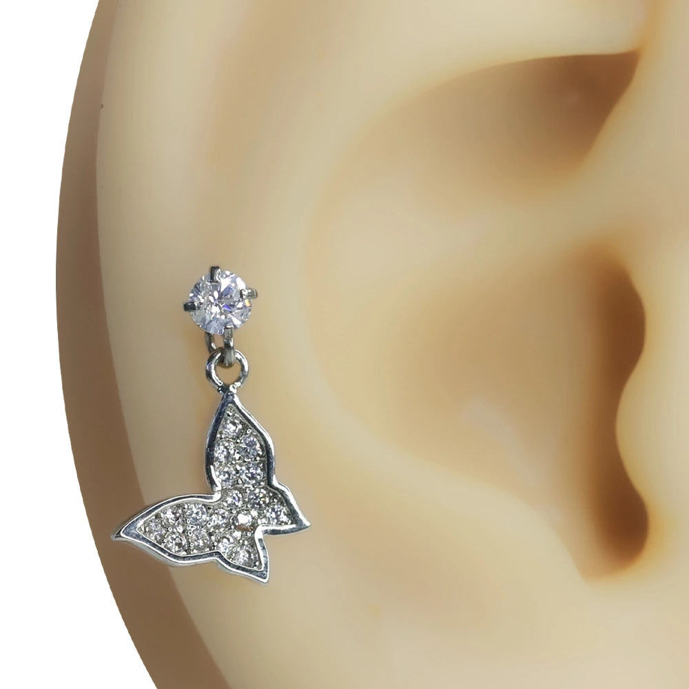 Kulak üzerinde sergilenen zirkon taşlı kelebek tragus helix kıkırdak piercing.