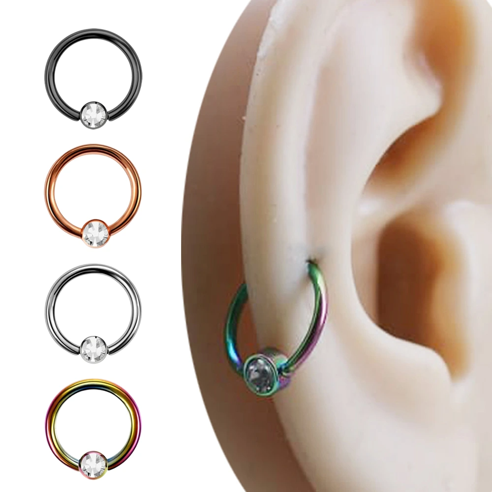 Tekli şeffaf zirkon taşlı halka formuna sahip; siyah, rose, gümüş ve gökkuşağı renk seçenekleri yan yana dizilmiş çelik piercing modelleri