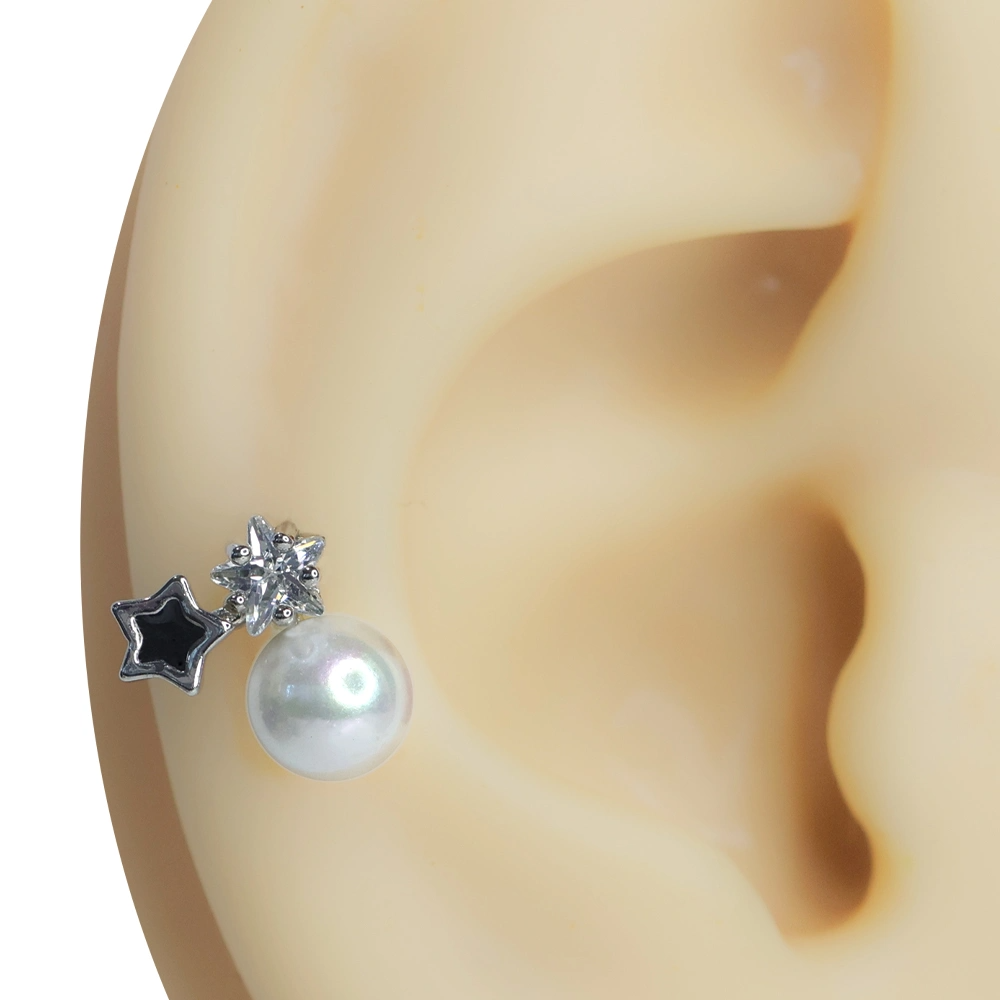 Kulak kıkırdağında sergilenen zirkon taşlı yıldız ve inci detaylı tragus helix kıkırdak piercing