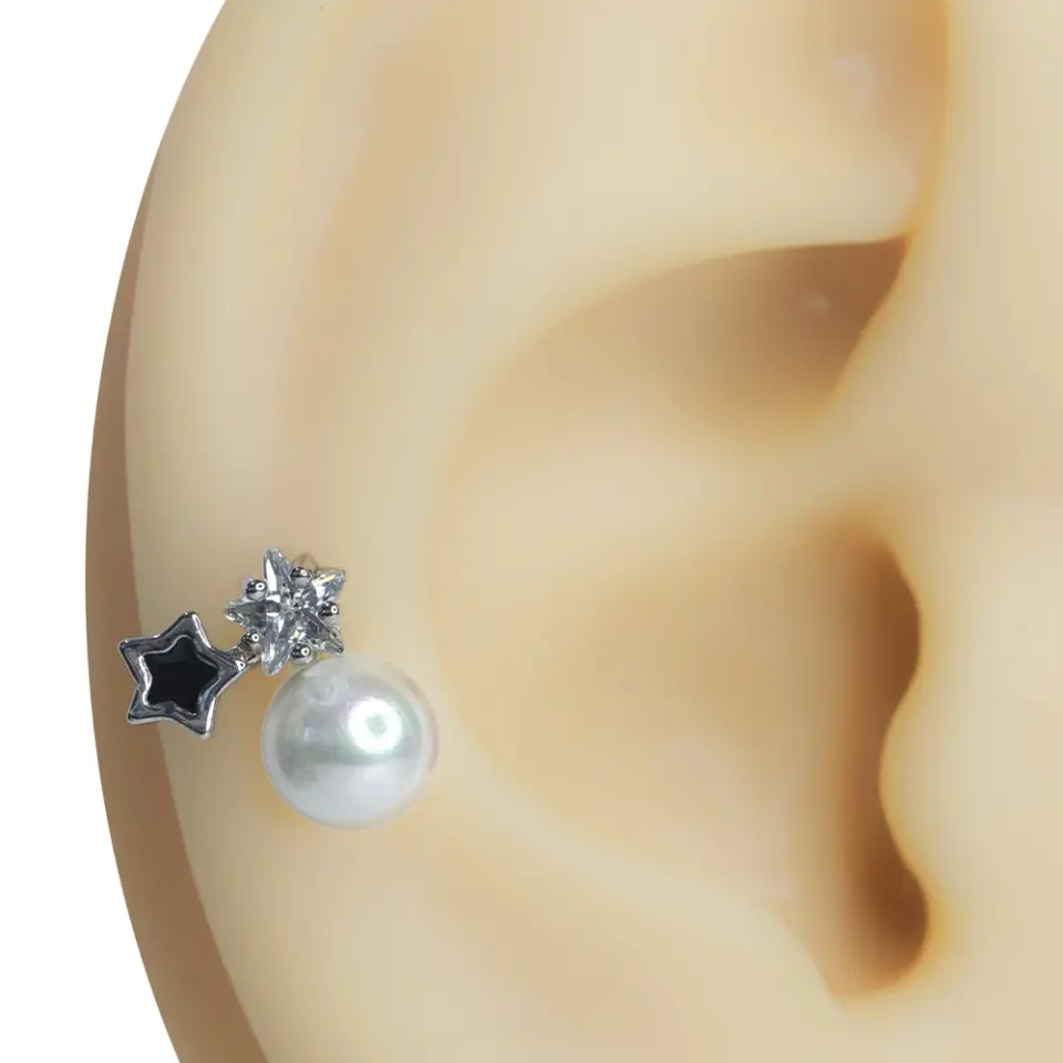 Kulak kıkırdağında sergilenen zirkon taşlı yıldız ve inci detaylı tragus helix kıkırdak piercing