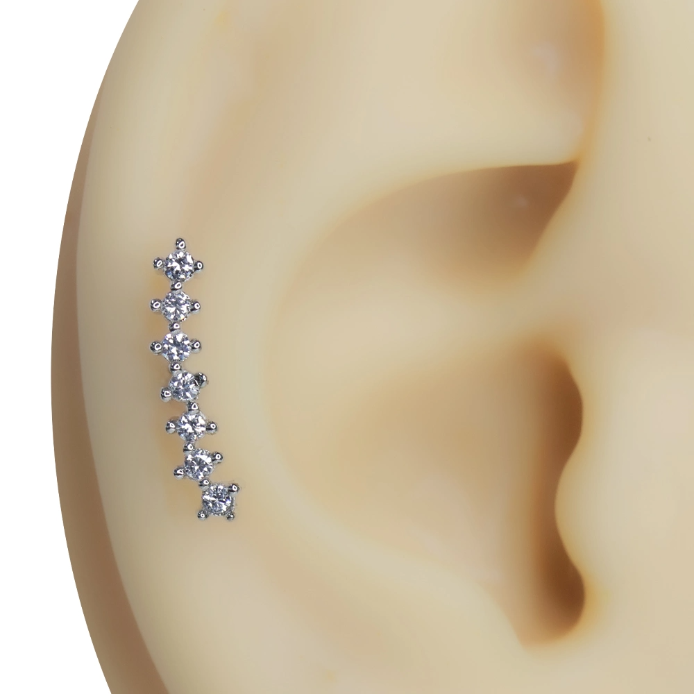 Kulak üzerinde sergilenen kavisli yedi taşlı gümüş renkli tragus helix kıkırdak piercing