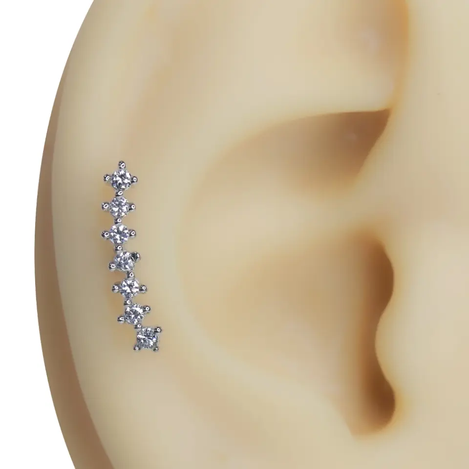 Kulak üzerinde sergilenen kavisli yedi taşlı gümüş renkli tragus helix kıkırdak piercing