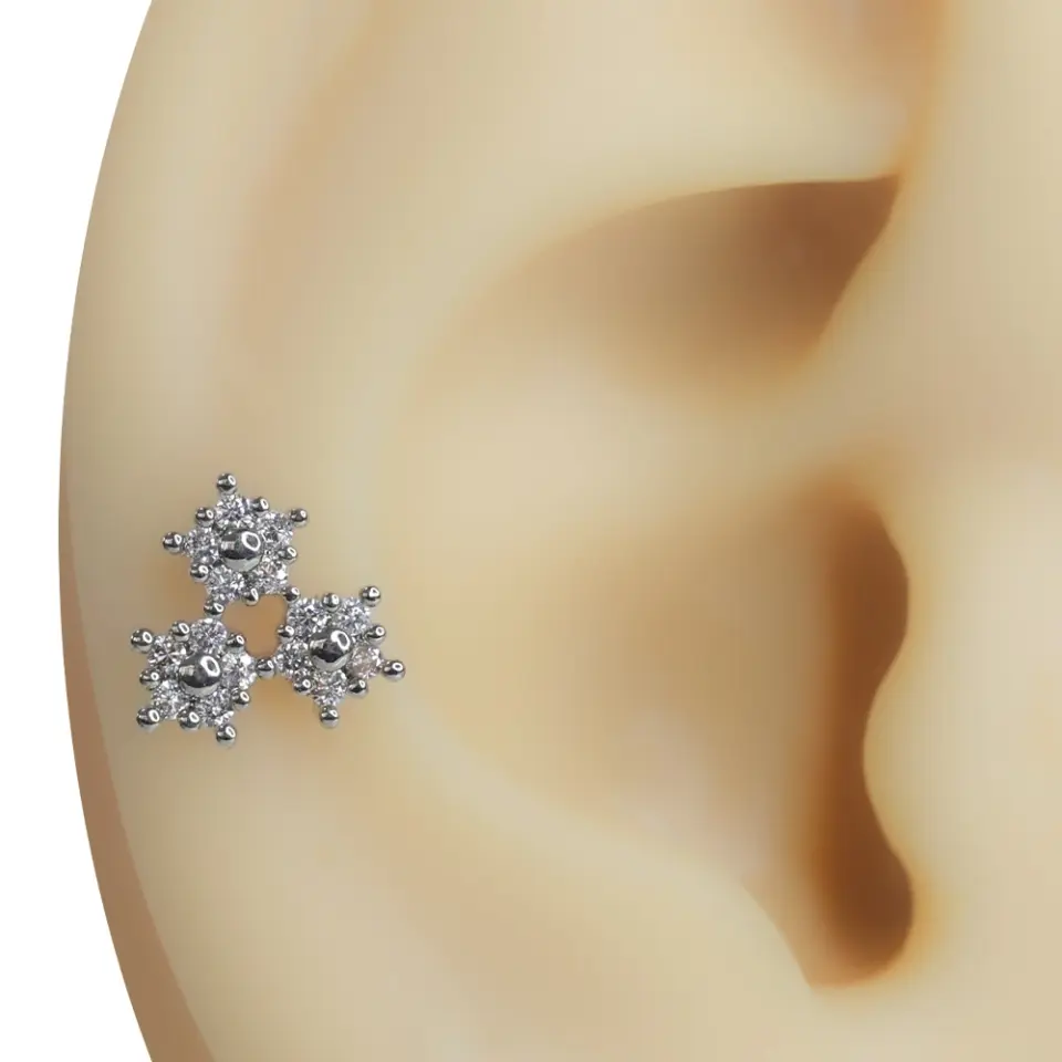Kulak üzerinde üçlü çiçek formunda sergilenen zirkon taşlı tragus helix kıkırdak piercing modeli