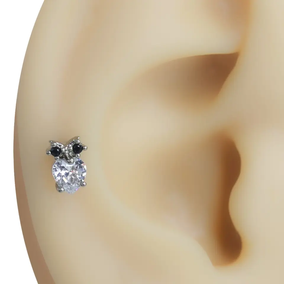 Kulak üzerinde sergilenen baykuş figürlü ve zirkon taşlı tragus helix kıkırdak piercing modeli