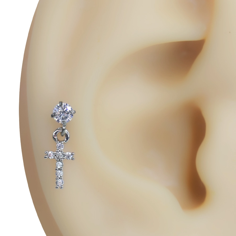 Kulak kıkırdağında sallantılı haç formunda duran zirkon taşlı tragus helix kıkırdak piercing