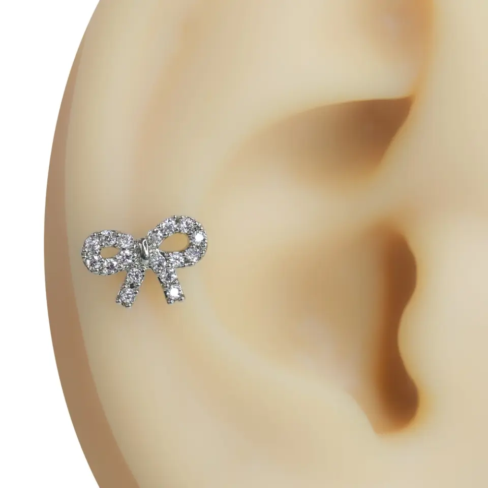 Kulak kıkırdağı üzerinde sergilenen zirkon taşlı fiyonk figürlü tragus helix kıkırdak piercing