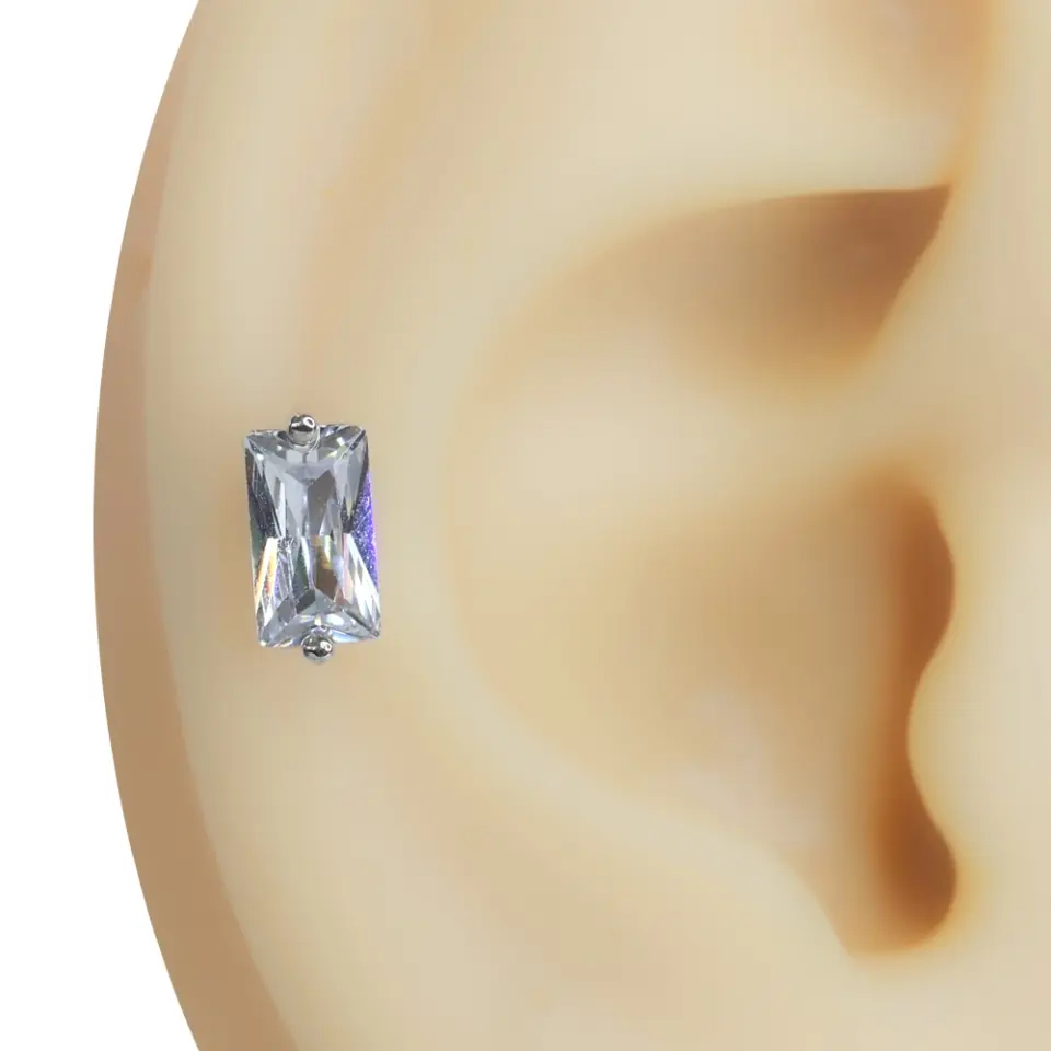 Kulak kıkırdağı üzerinde sergilenen dikdörtgen formlu zirkon taşlı tragus helix kıkırdak piercing