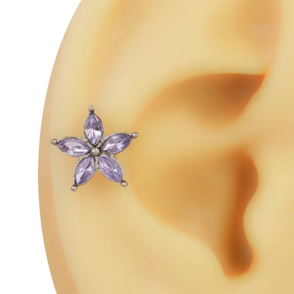 Kıkırdak üzerinde sergilenen lila taşlı ve beş yapraklı çiçek figürlü helix piercing modeli.