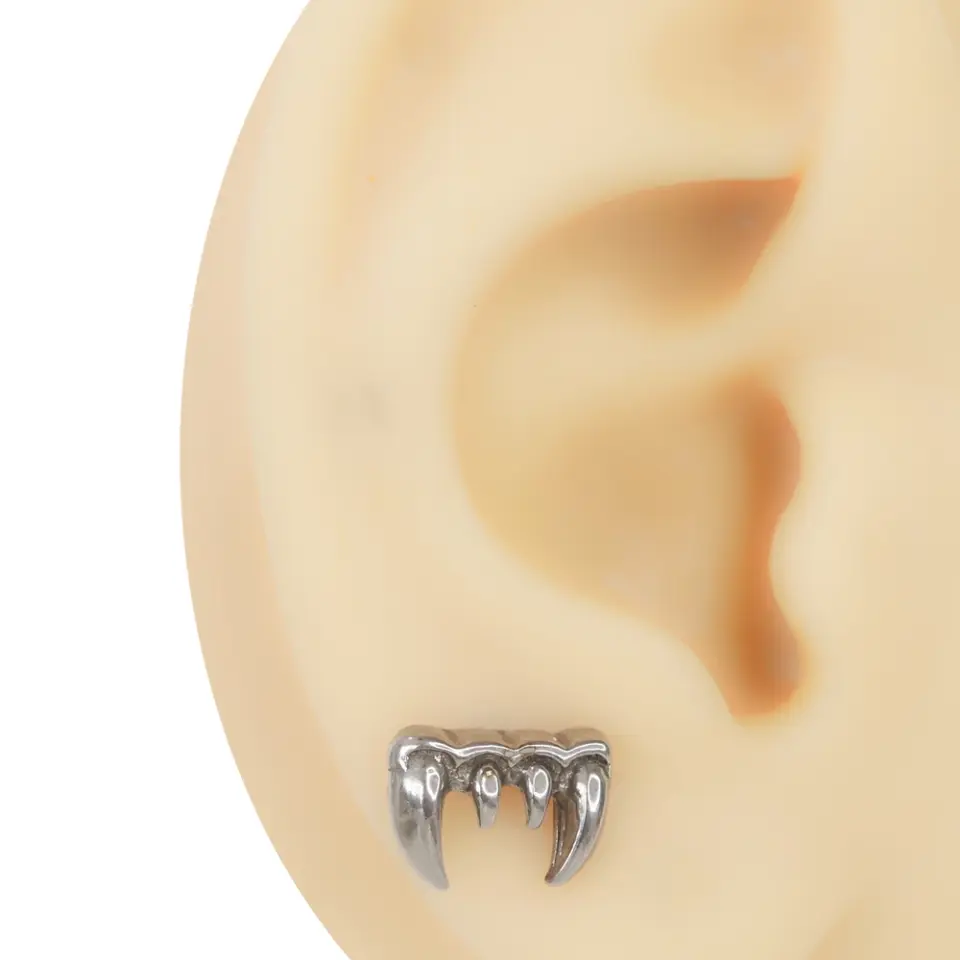 Kulak maketinin lobe bölgesine takılmış gümüş renkli 316L cerrahi çelik vampir dişi figürlü piercing