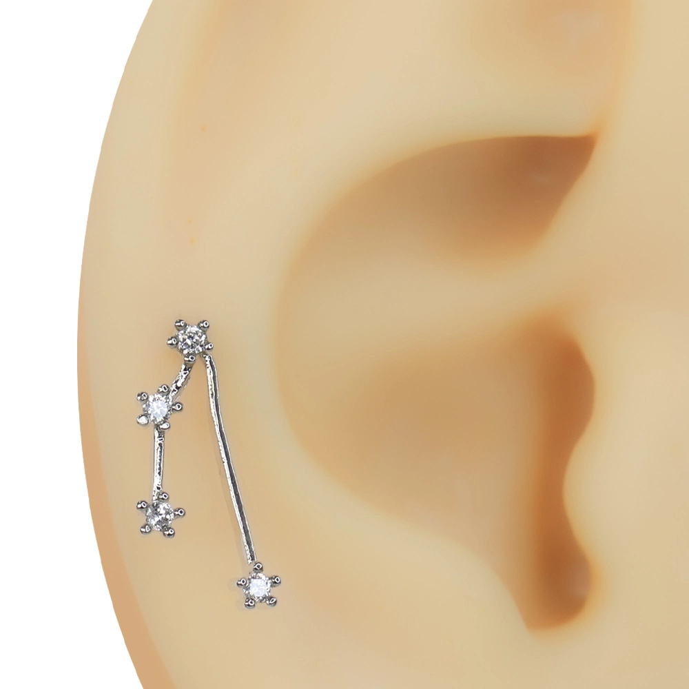 Kulak üzerinde dikey formda duran zirkon taşlı Yıldız Yolu tragus helix kıkırdak piercing