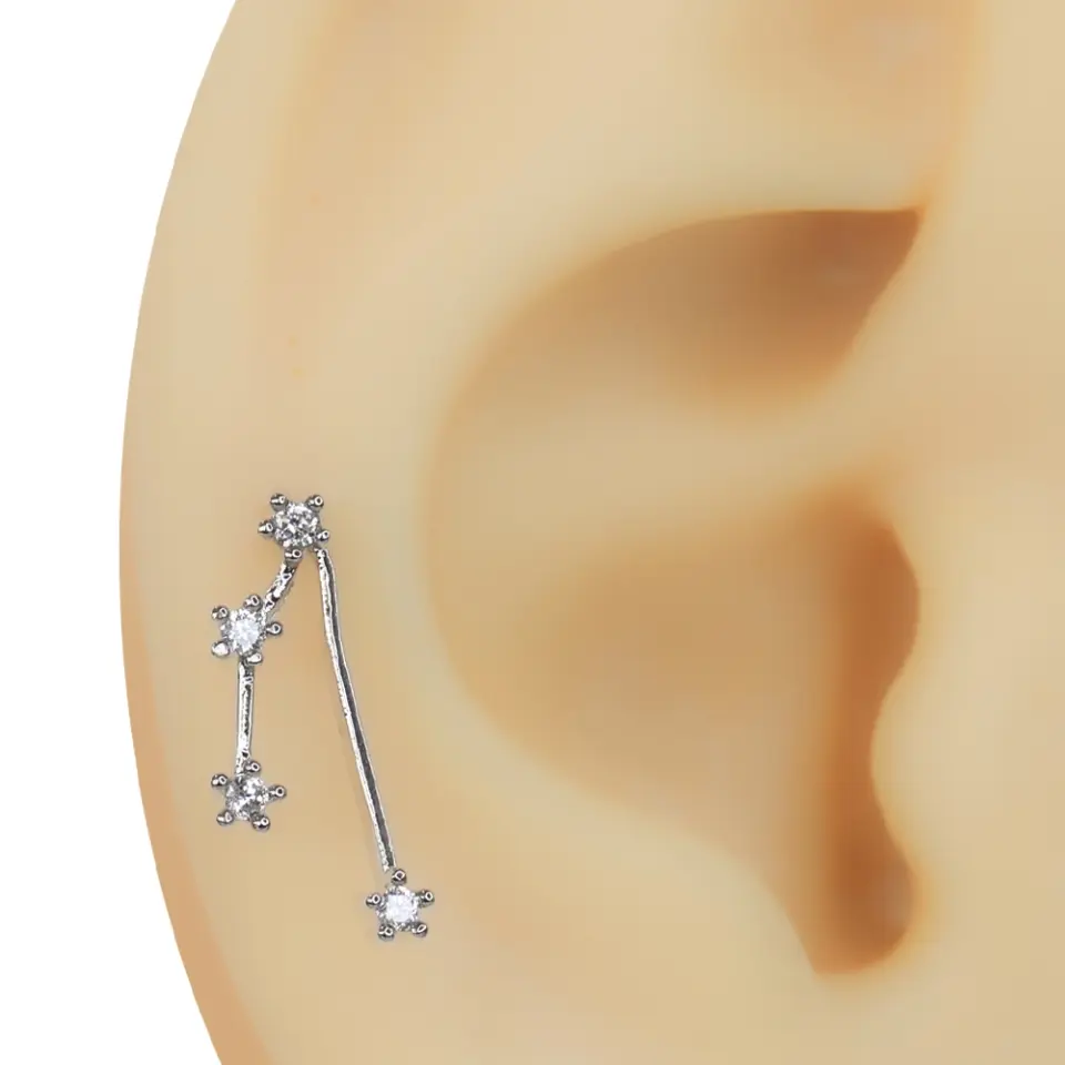 Kulak üzerinde dikey formda duran zirkon taşlı Yıldız Yolu tragus helix kıkırdak piercing