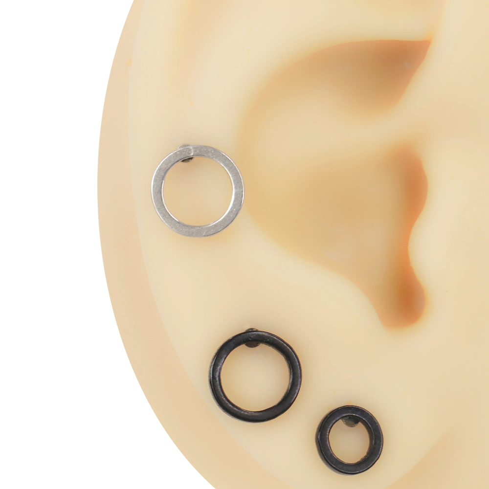 Kulak maketi üzerinde sergilenen gümüş ve siyah renkli içi boş dairesel çember objeli cerrahi çelik kıkırdak piercingleri