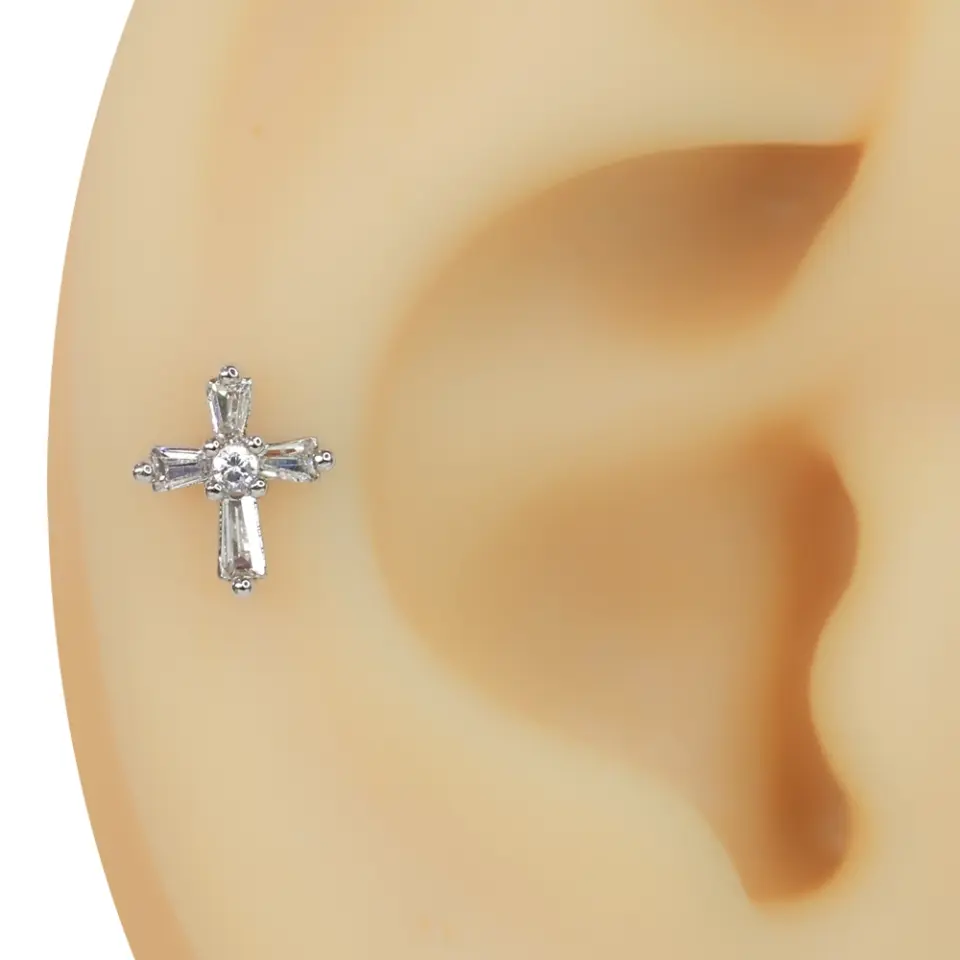 Kulak kıkırdağında sergilenen zirkon taşlı haç figürlü tragus helix kıkırdak piercing