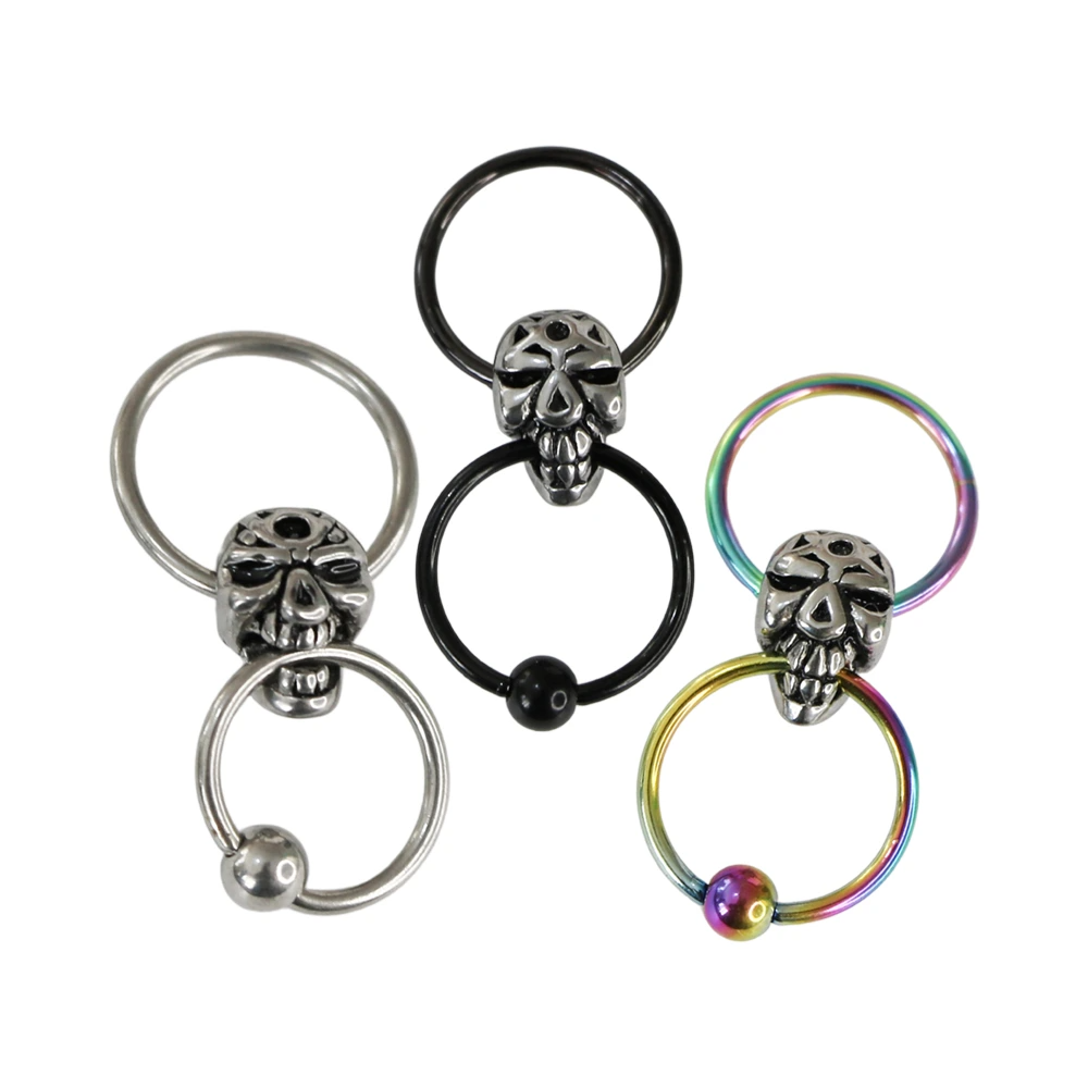Yan yana sergilenen gümüş, siyah ve gökkuşağı renkli çemberli kurukafa cerrahi çelik halka piercing modelleri