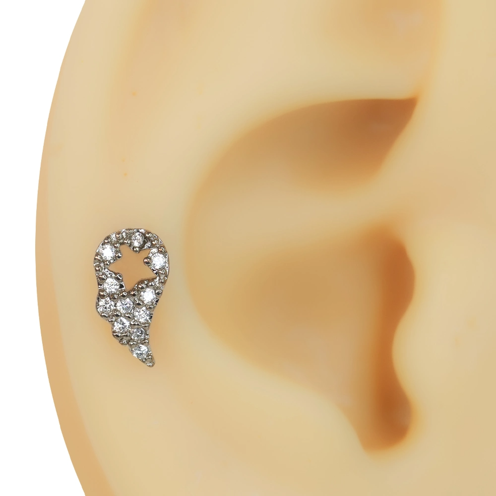 Kulak üzerinde sergilenen yıldız detaylı kanat figürlü zirkon taşlı tragus helix kıkırdak piercing