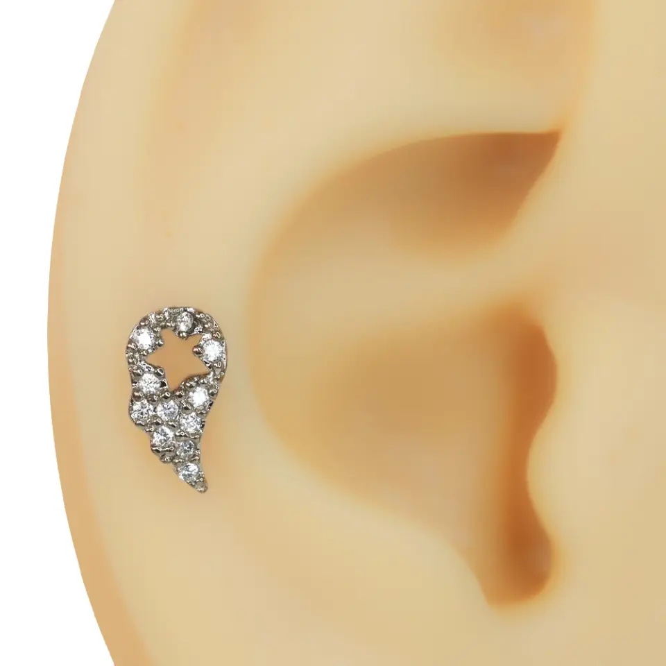 Kulak üzerinde sergilenen yıldız detaylı kanat figürlü zirkon taşlı tragus helix kıkırdak piercing